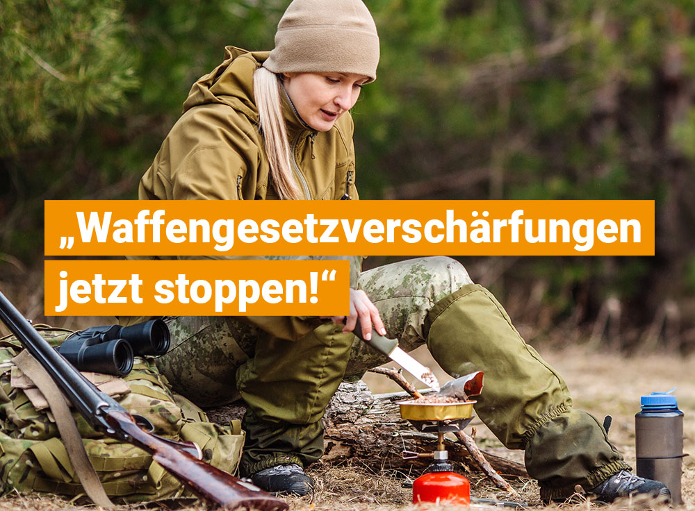 Frau in Outdoor-Kleidung sitzt im Wald und kocht auf einem Gaskocher; neben ihr liegen ein Gewehr und Ausrüstung, darüber eingeblendeter Text „Waffengesetzverschärfungen jetzt stoppen!“.